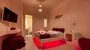 Une chambre à coucher avec un lit, un téléviseur et une table de chevet éclairée en rouge.