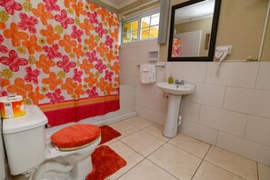 A bathroom with a toilet, sink, and shower curtain with a floral pattern.