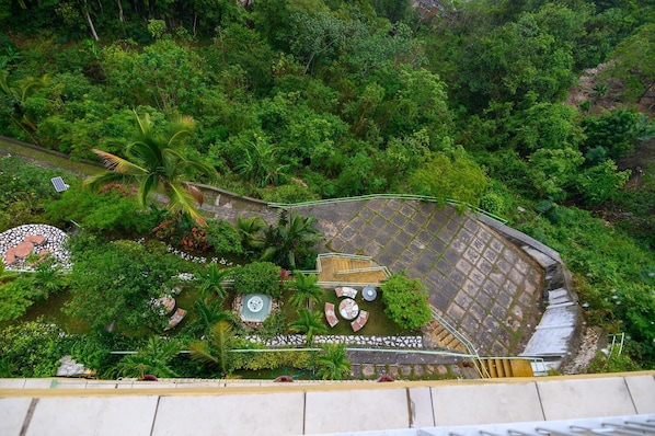 A circular stone patio with a central fountain, surrounded by lush greenery and palm trees. - Look Out Point at Promontory Ridge (Kingston)
