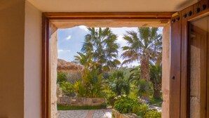 A stone pathway leading to a garden with palm trees and a thatched roof structure. - Finca Ses Cases Noves (Sant Llorenc des Cardassar)