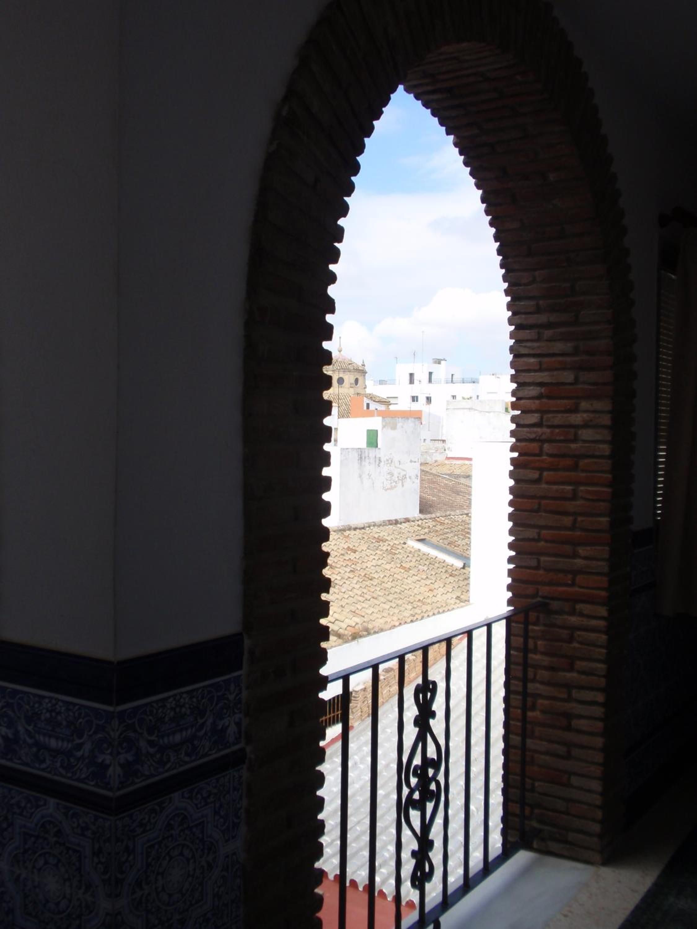An arched doorway leading to a balcony with a view of buildings.