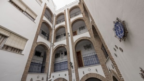 Un edificio de varios pisos con balcones arqueados y una placa decorativa en la pared.