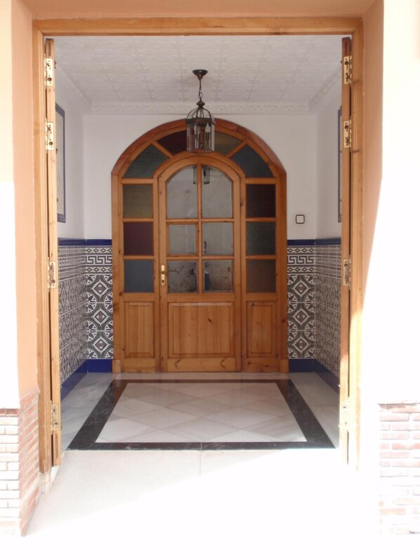 A wooden arched door with glass panels and a hanging light fixture. - Hotel San Andrés (Jerez de la Frontera)