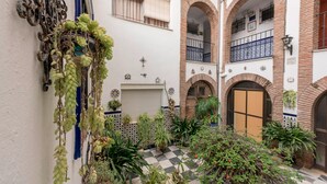 Un patio con suelo a cuadros, plantas en macetas y una pieza decorativa de metal.