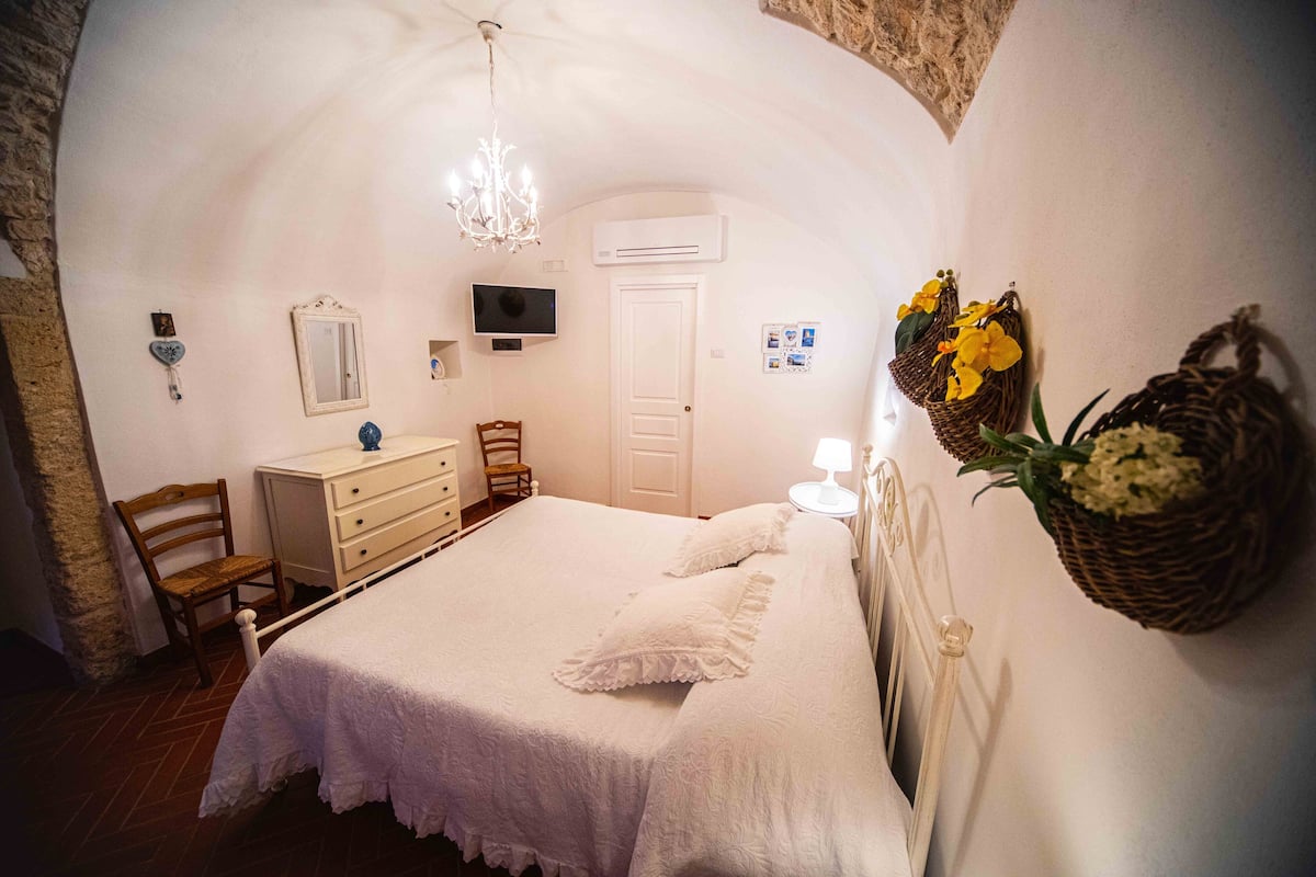 A cozy bedroom with a bed, dresser, chair, and decorative items.