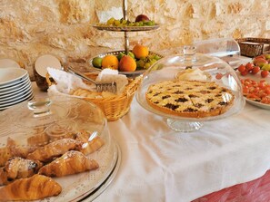 A buffet table with a variety of food items including pastries, fruits, and a pie. - Agriturismo Masseria Del Crocifisso (Polignano a Mare)