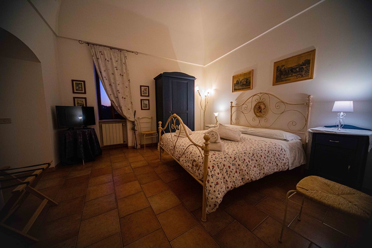 A bedroom with a bed, a wardrobe, a bedside table, a lamp, and a television.