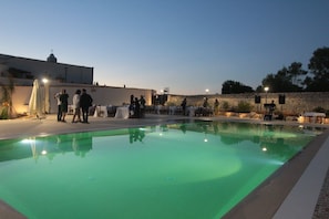 Un espace piscine avec un mur en pierre et un bâtiment en arrière-plan.