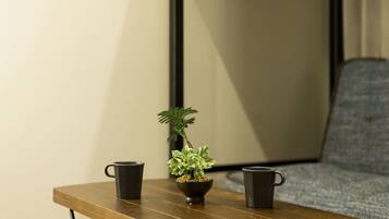A wooden table with two black mugs and a small potted plant.