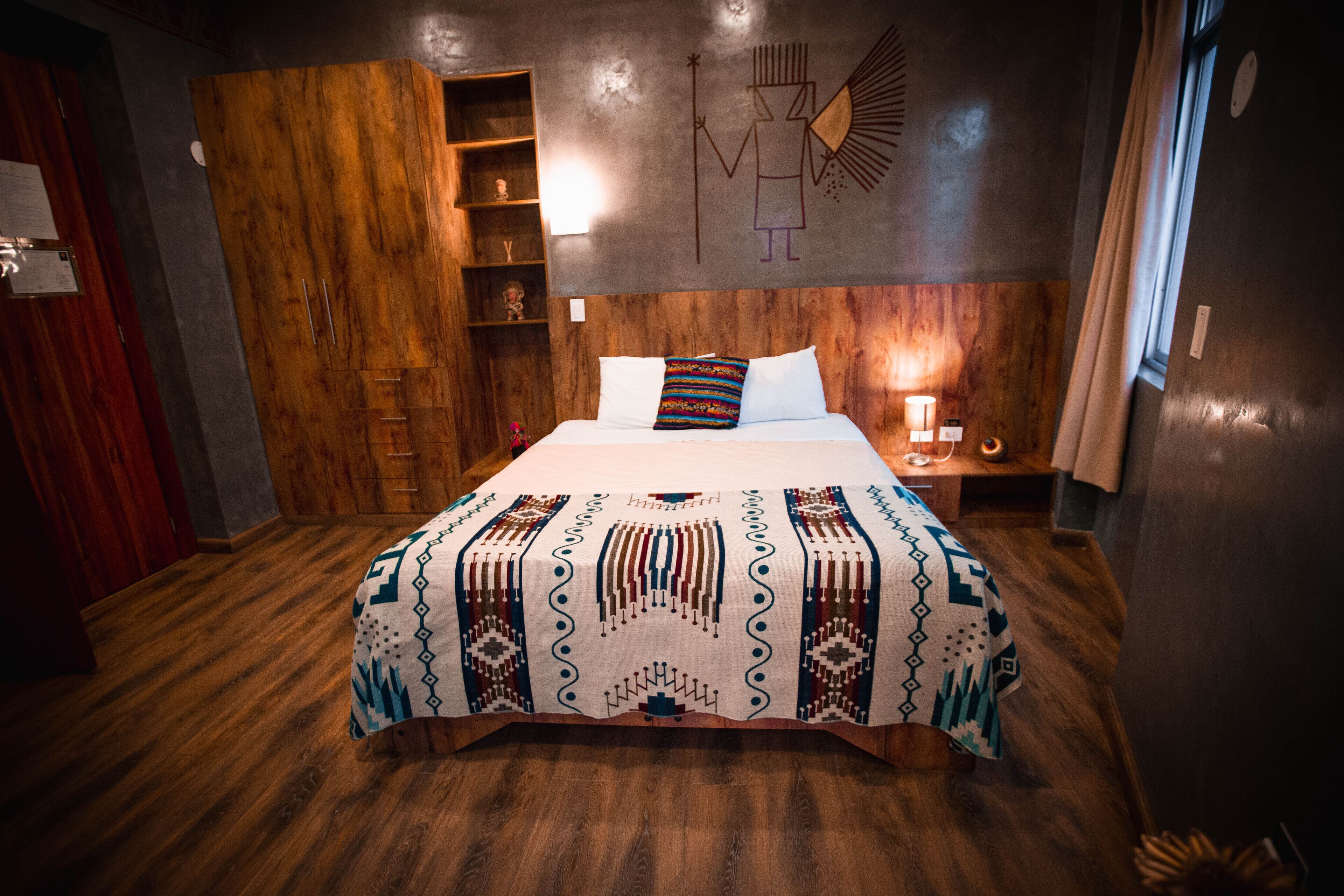 Een hotelkamer met een groot bed, een houten garderobe en een wandplank.