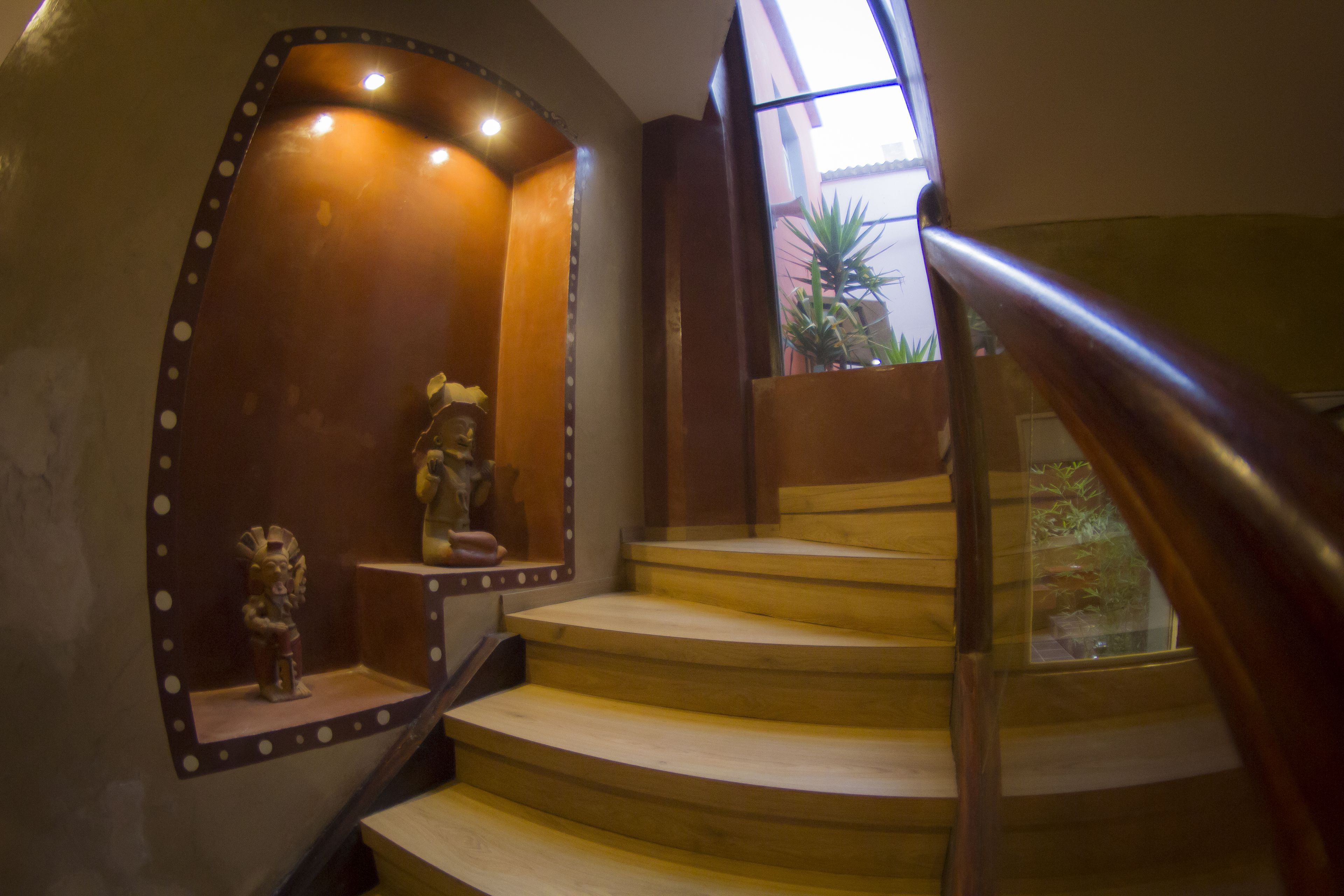 A wooden staircase with a handrail, a small statue, and a window with a view of plants outside.