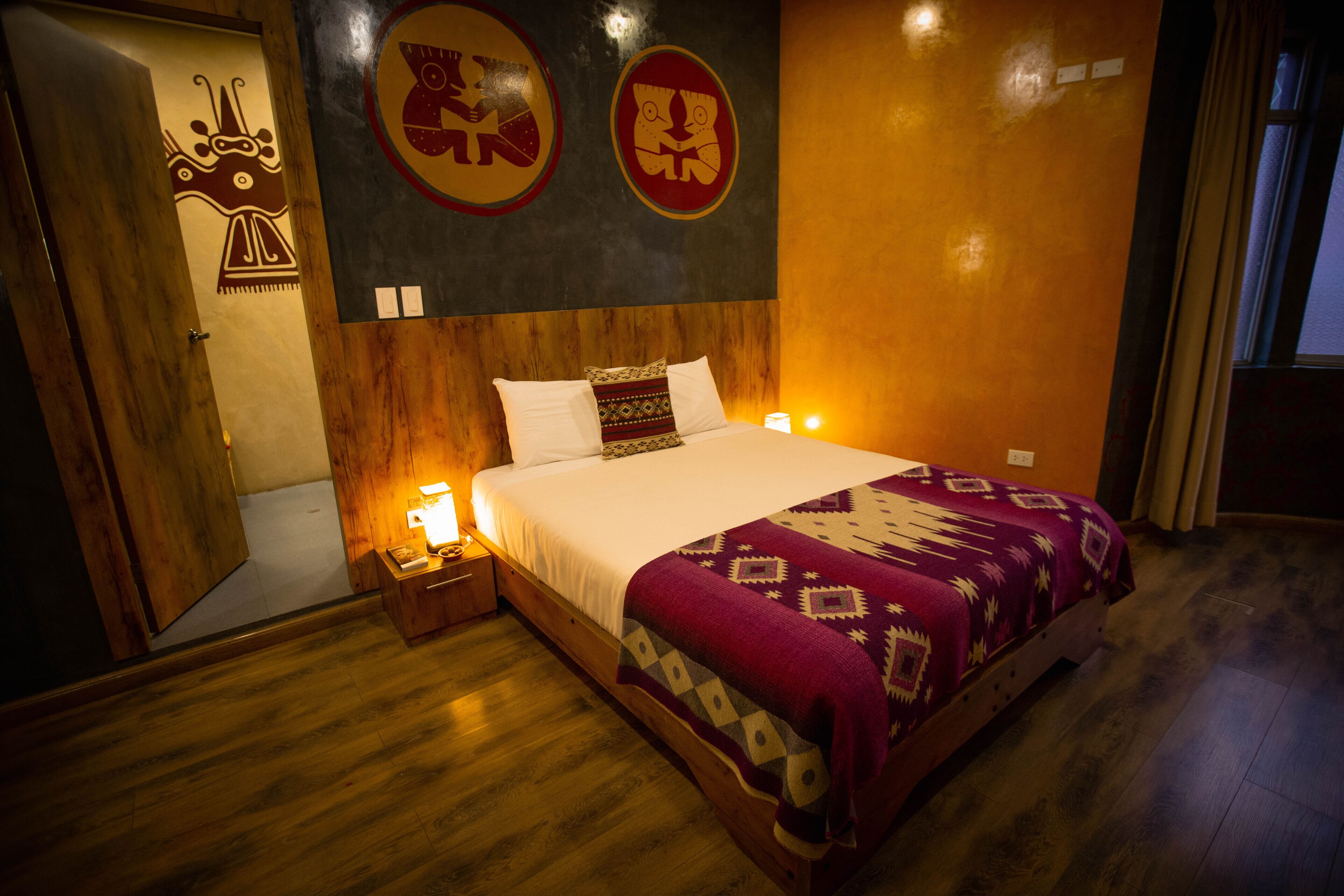 A bedroom with a wooden bed, a nightstand with a lamp, and a wall with two circular wall art pieces.