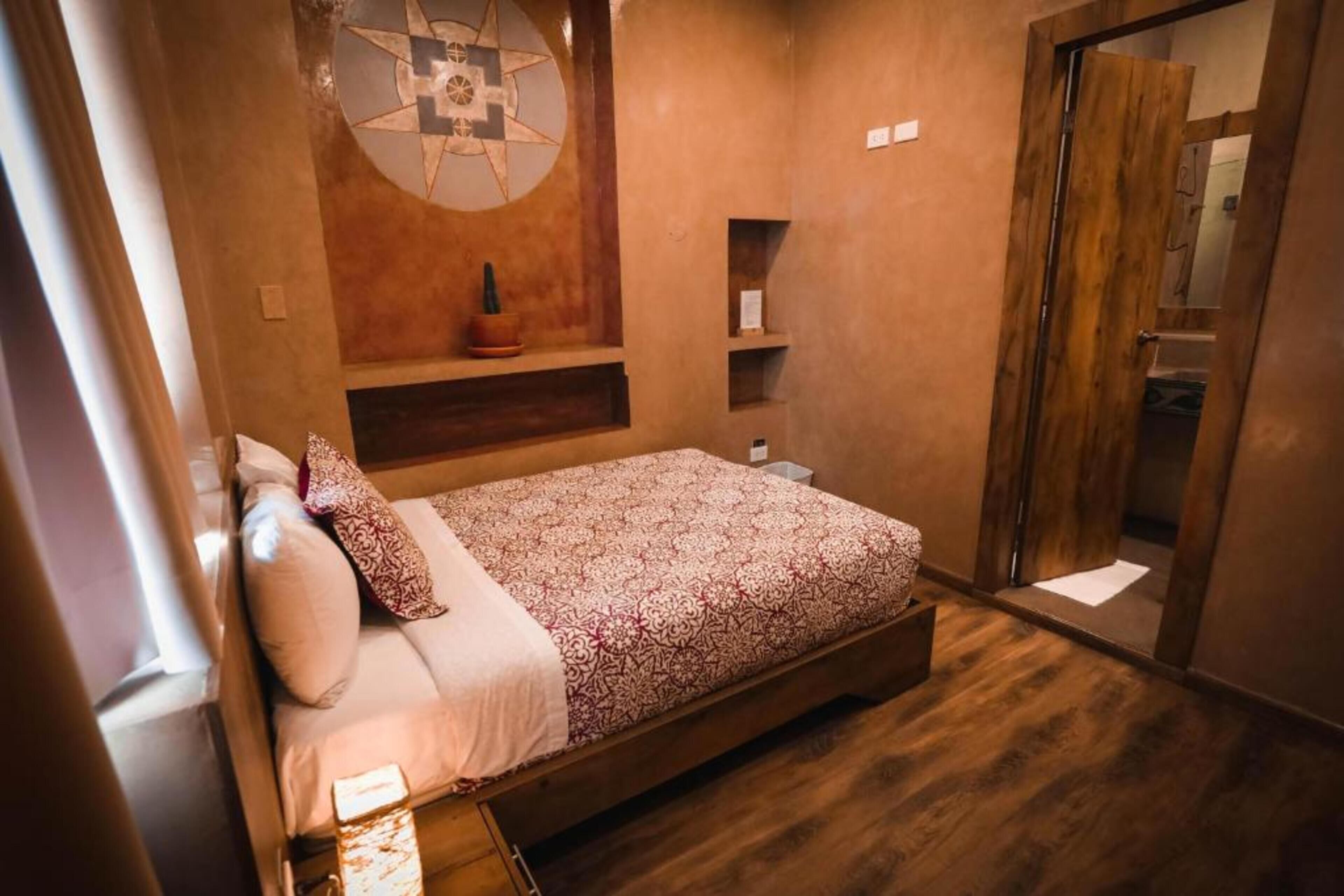 Un dormitorio con cama, repisa en la pared, puerta y ventana.