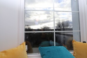 Ein Fenster mit Blick auf einen bewölkten Himmel und kahle Bäume.