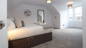 A bedroom with a large bed, a round mirror, and a window with a view. - Dollar Apartments at 41 (Dollar)