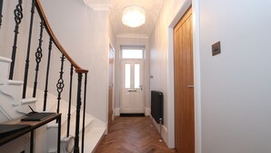 A hallway with a wooden floor, a white door, and a black TV on the wall. - Dollar Apartments at 41 (Dollar)