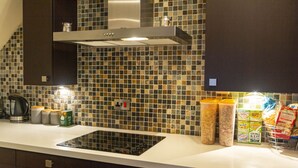 A modern kitchen with a tiled backsplash, a built-in stove, and various kitchen appliances. - The Apartment No 2 The Old Red King Pub (Manchester)