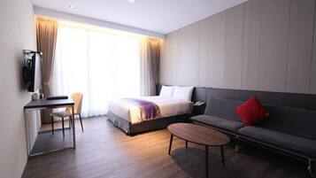 Una habitación de hotel moderna con cama, sofá, escritorio y televisión.