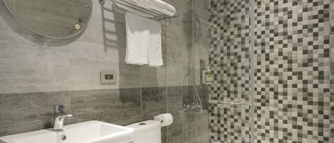 A modern bathroom with a glass-enclosed shower, a white sink, and a toilet.
