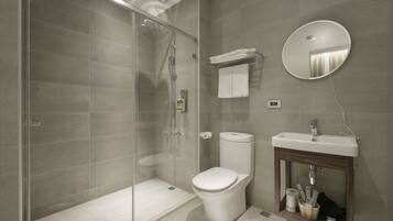 A modern bathroom with a glass-enclosed shower, a toilet, and a sink with a mirror above it.
