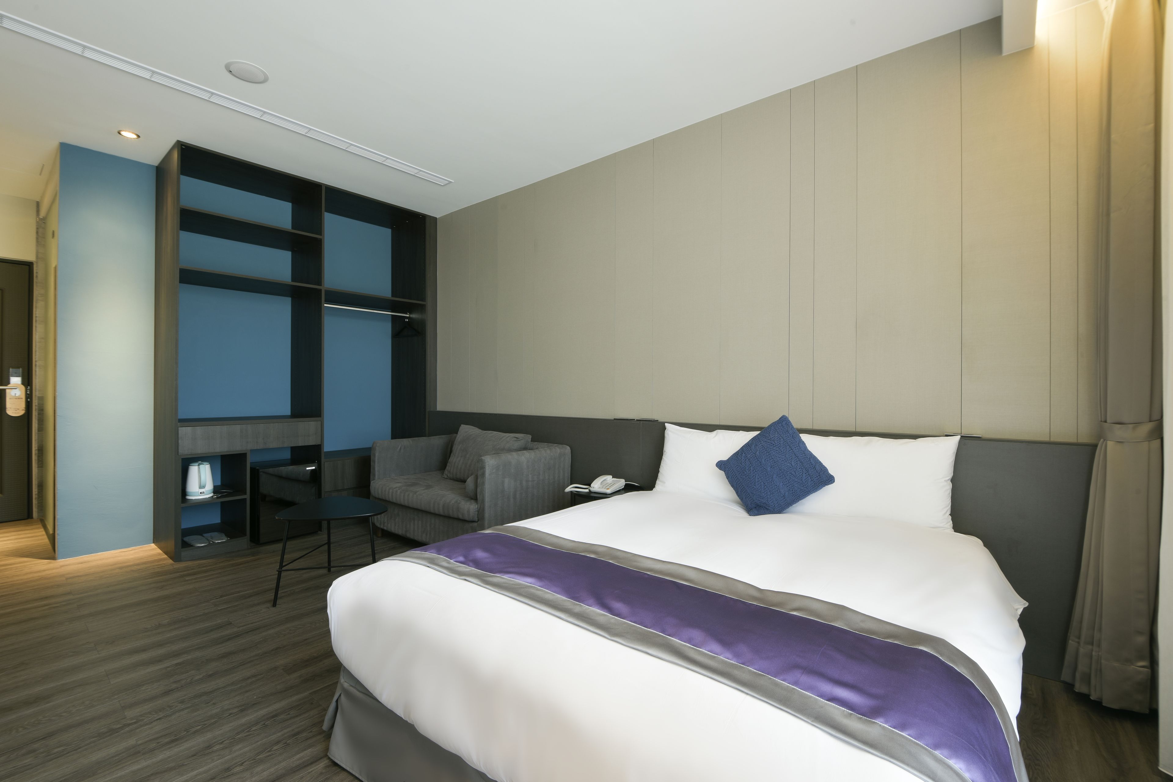 Ein modernes Hotelzimmer mit einem großen Bett, einem Schreibtisch und einem Sessel.