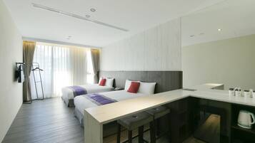 Une chambre d’hôtel moderne équipée d’un grand lit, d’un bureau et d’une kitchenette.