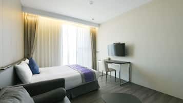 A modern hotel room with a bed, a desk, a TV, and a sofa.
