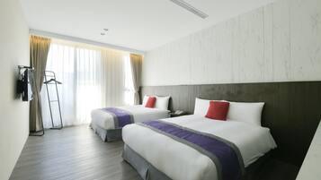 A hotel room with two beds, a wardrobe, a desk, and a window with curtains.