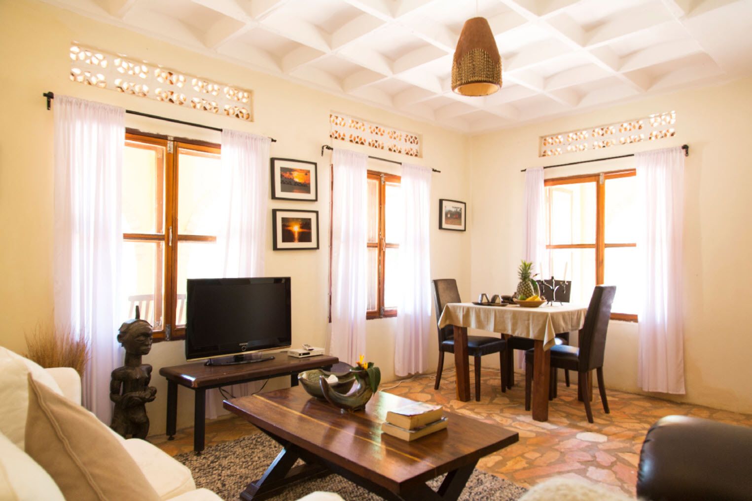 Una sala de estar con televisor, una mesa de centro y un comedor con mesa y sillas.