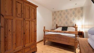 Un dormitorio con una cama de madera, un armario y una mesita de noche.