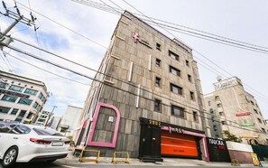 A multi-story building with a prominent pink door and signage for a hotel named 'MADOKA'. - Madoka (Gyeongju)