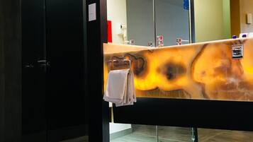 Un baño moderno con un espejo grande, un perchero y suelo de madera.