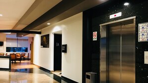 Un ascensor moderno con un cartel de prohibido fumar, un cesto de basura y un contenedor para reciclaje.