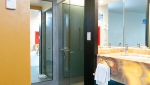 Un baño moderno con un espejo grande, puertas de ducha de vidrio y suelo de madera.