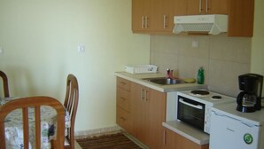 A small kitchen with wooden cabinets, a microwave, a coffee maker, and a sink. - Kleio Studios (Platanias)