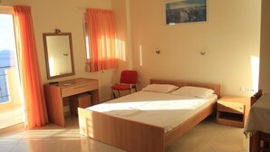 A bedroom with a wooden bed, a desk, a chair, a mirror, and a window with curtains. - Kleio Studios (Platanias)