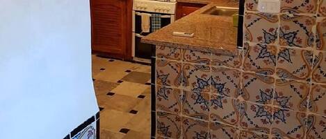 Una cocina con baldosas estampadas, una estufa a gas y un lavamanos.