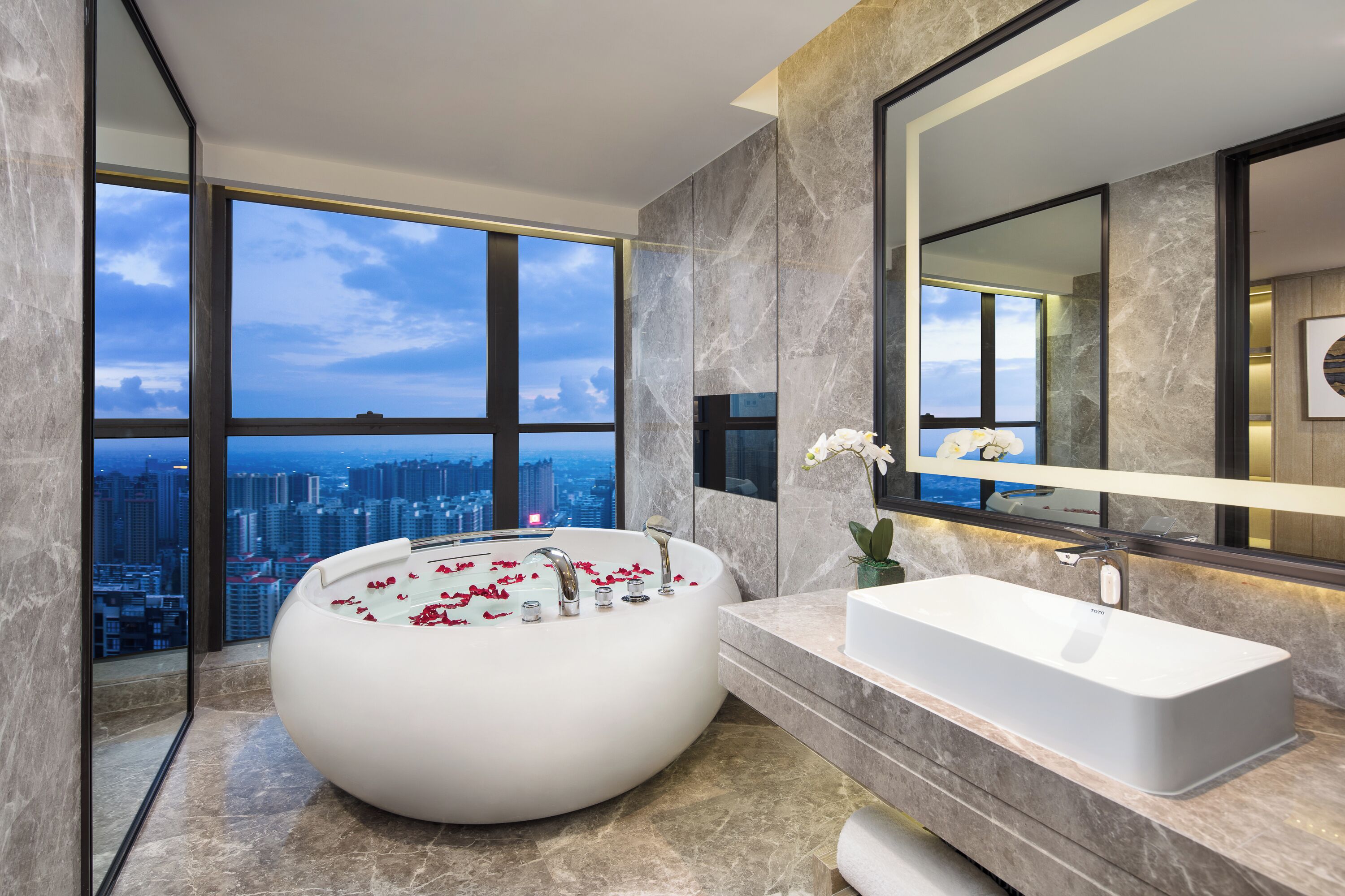 Une salle de bain moderne avec une grande baignoire, un lavabo rectangulaire et un grand miroir.