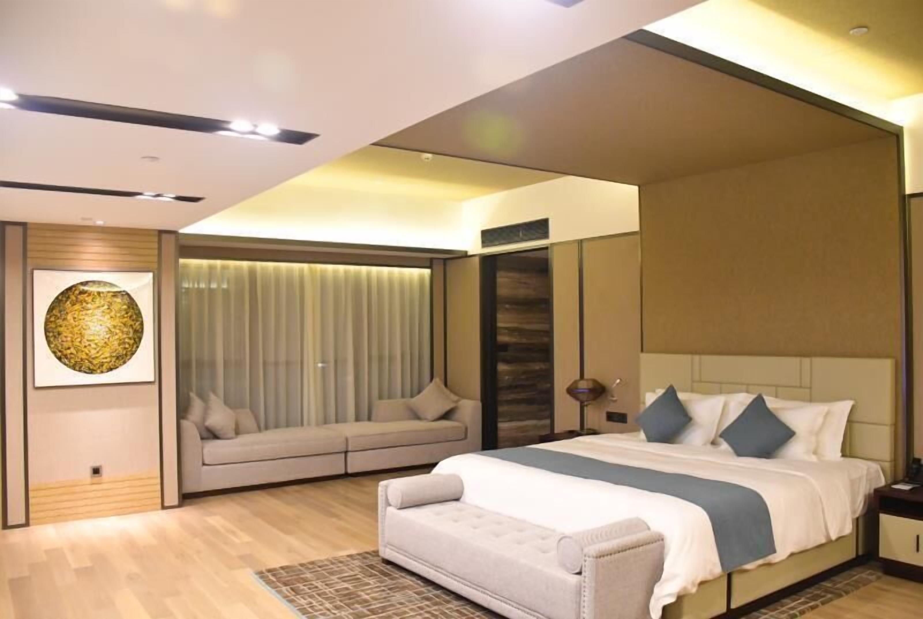 Une chambre d’hôtel moderne dotée d’un grand lit, d’un canapé et d’un coin salon agrémenté de rideaux.