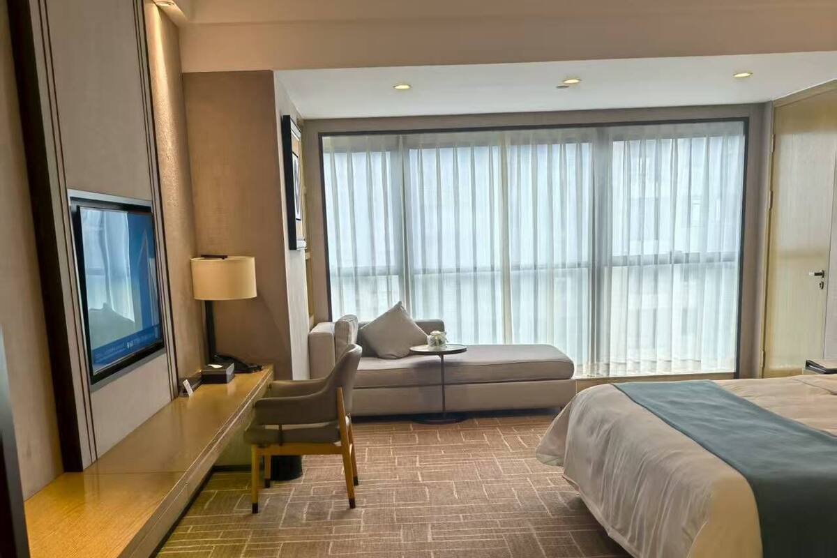 A hotel room with a bed, a sofa, a TV, and a desk.