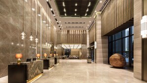 Eine geräumige Lobby mit einer Rezeption, einer Sitzecke und großen Fenstern.
