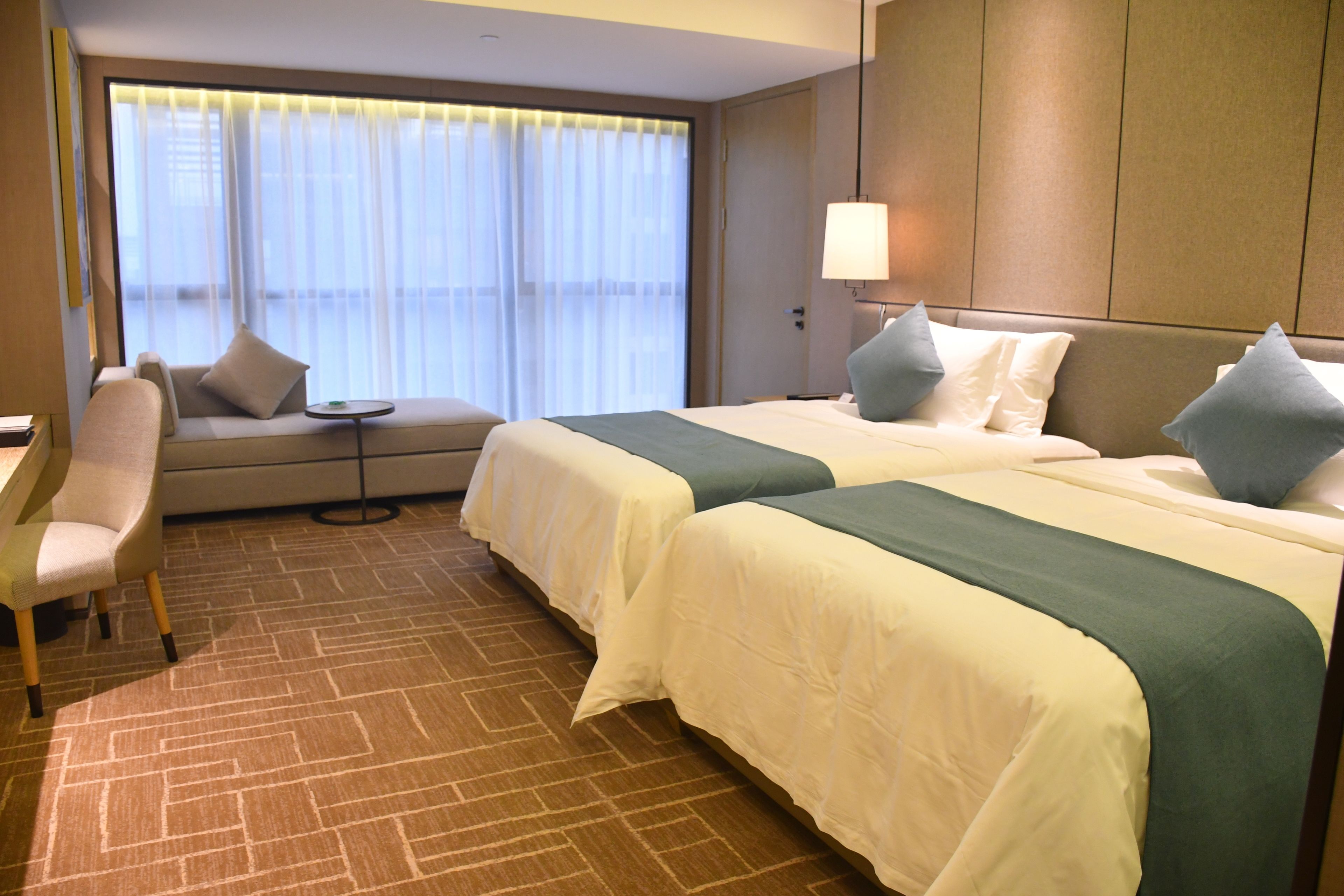 A hotel room with two beds, a sofa, a desk, and a chair.