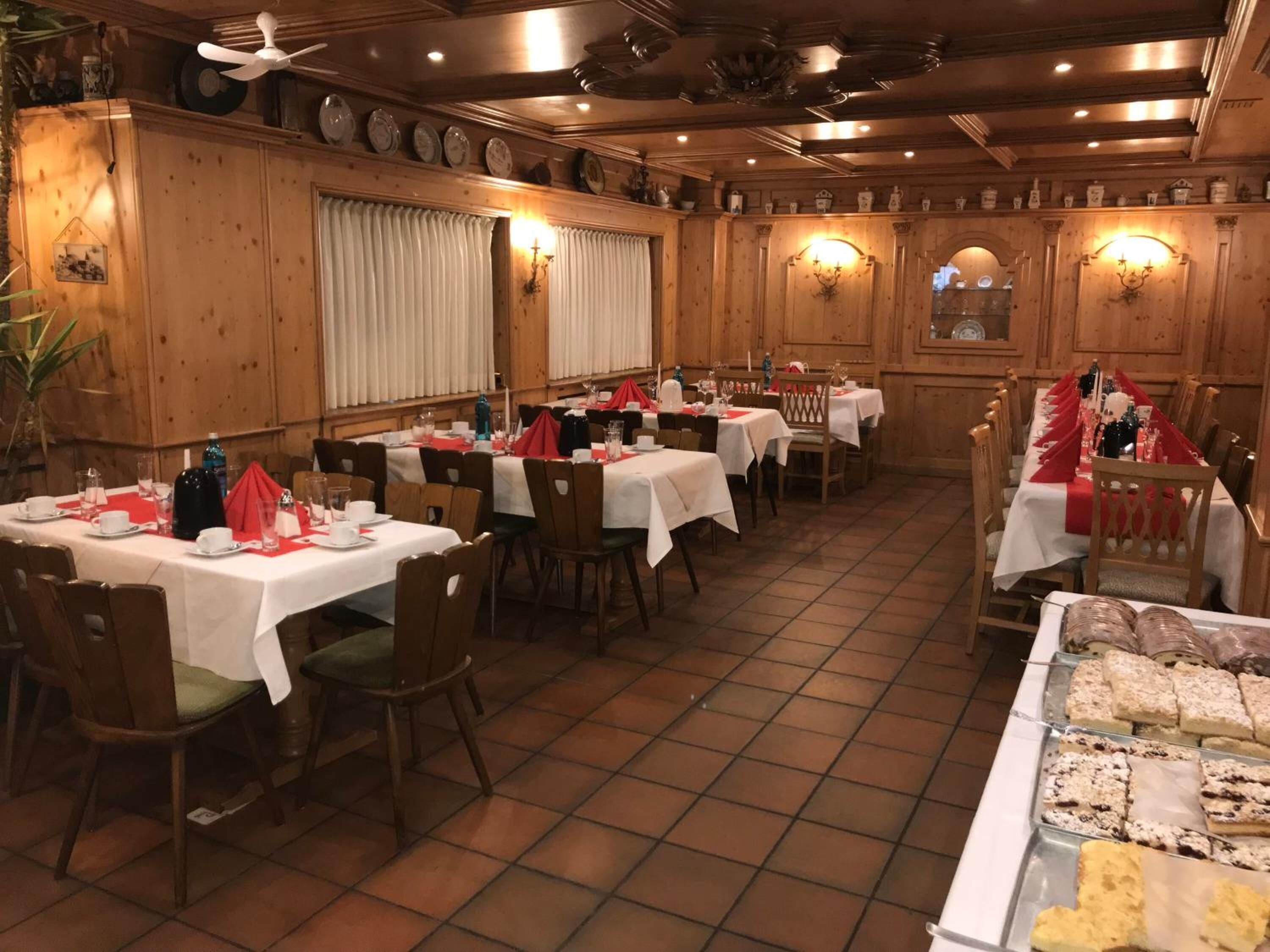 Een restaurant met houten wanden, witte tafelkleden en rode servetten.
