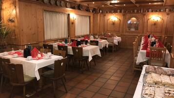 Ein Restaurant mit Holzwänden, weißen Tischdecken und roten Servietten.
