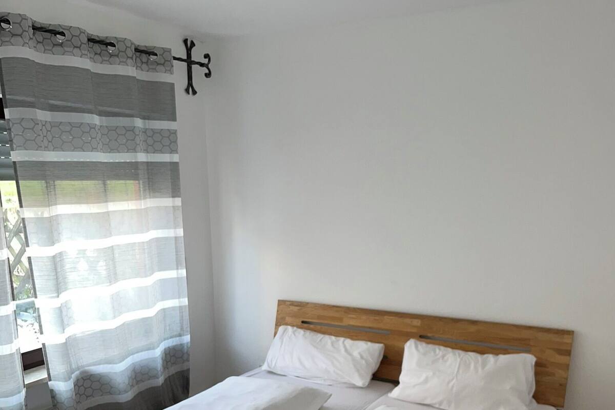 A bed with wooden headboard, white linens, and folded towels.