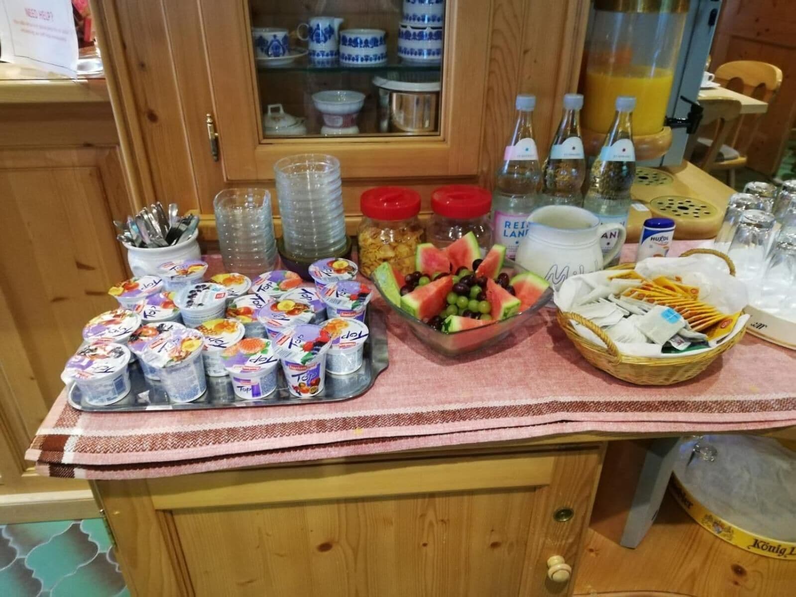 A breakfast buffet with yogurt cups, fruits, and various condiments.