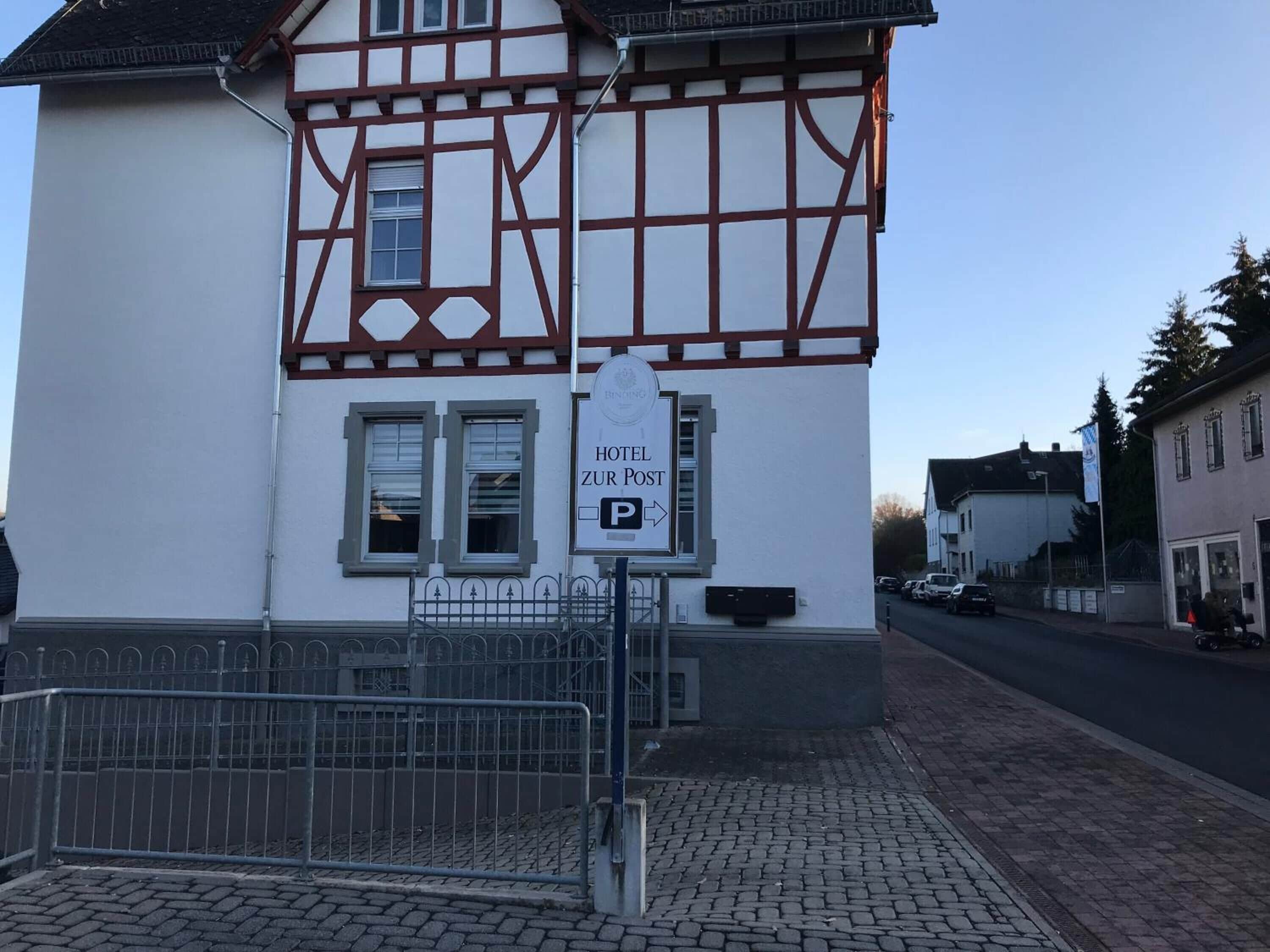 A traditional half-timbered building with a sign indicating a hotel named "Hotel Zur Post."
