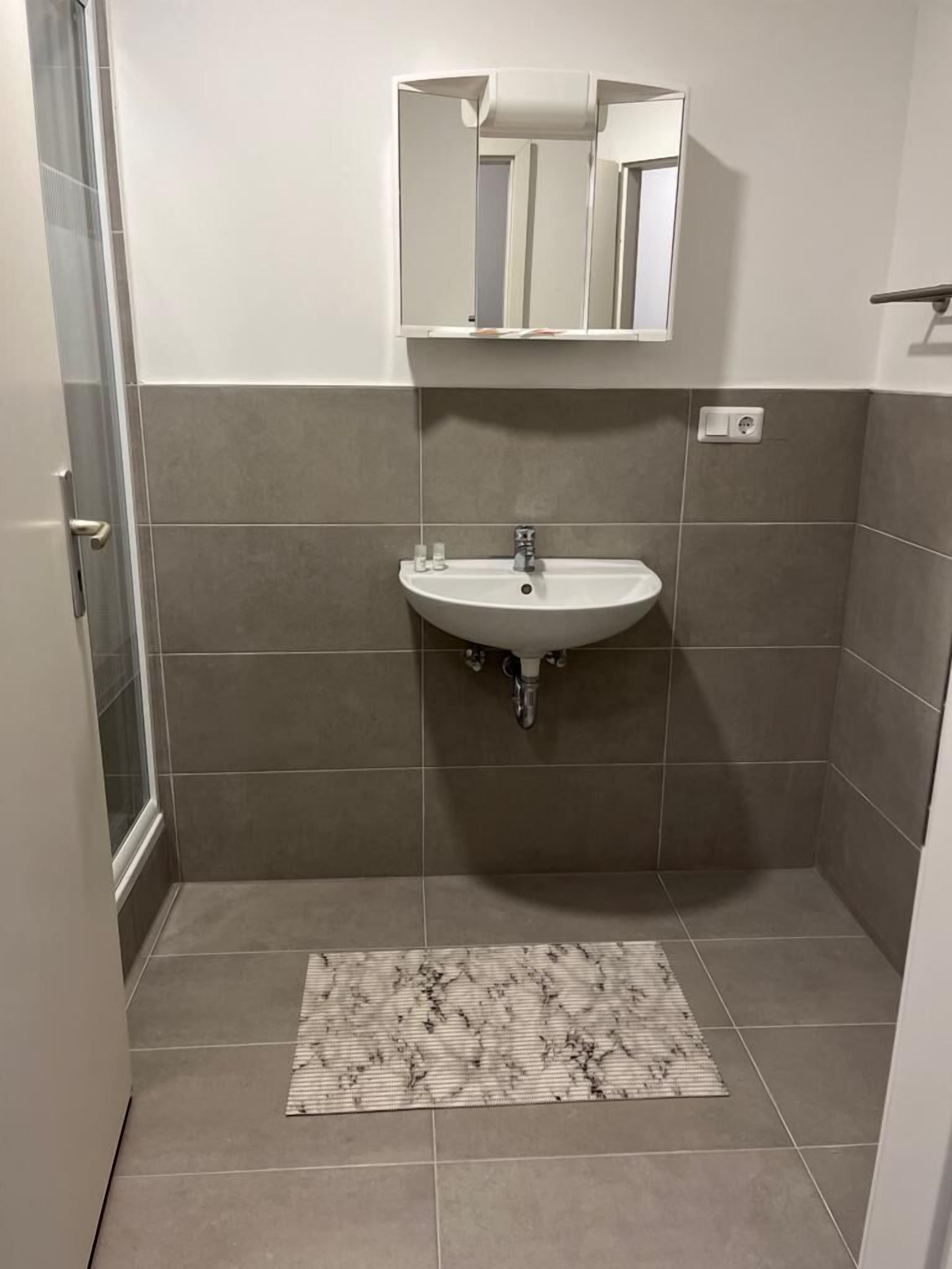 A bathroom with a sink, mirror, and tiled walls.