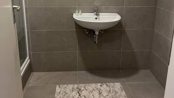 Un baño con lavamanos, espejo y paredes con azulejos.