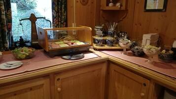 Une cuisine en bois dotée d’un meuble vitré où sont exposés des aliments, d’un coin café et de divers ustensiles de cuisine.